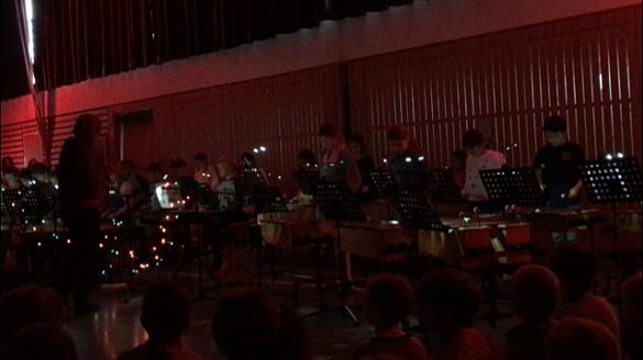 Auf dem Bild sind Schüler_innen an Instrumenten zu sehen. Zudem ist bunte Beleuchtung zu sehen.