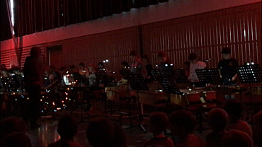 Auf dem Bild sind Schüler_innen an Instrumenten zu sehen. Zudem ist bunte Beleuchtung zu sehen.