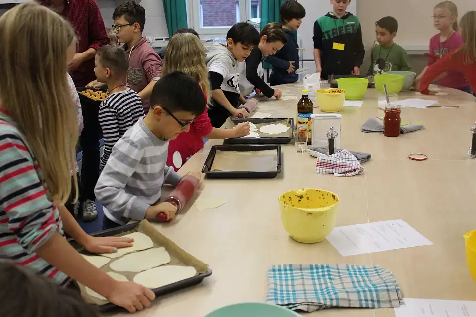 Auf dem Bild sind Sch&uuml;ler und Sch&uuml;lerinnen der Schule St. Magnus zu sehen, die eine T&uuml;rkische Pizza backen.