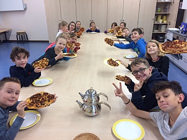 Auf dem Bild sind Schüler und Schülerinnen der Schule St. Magnus zu sehen, die eine Türkische Pizza in den Händen halten.