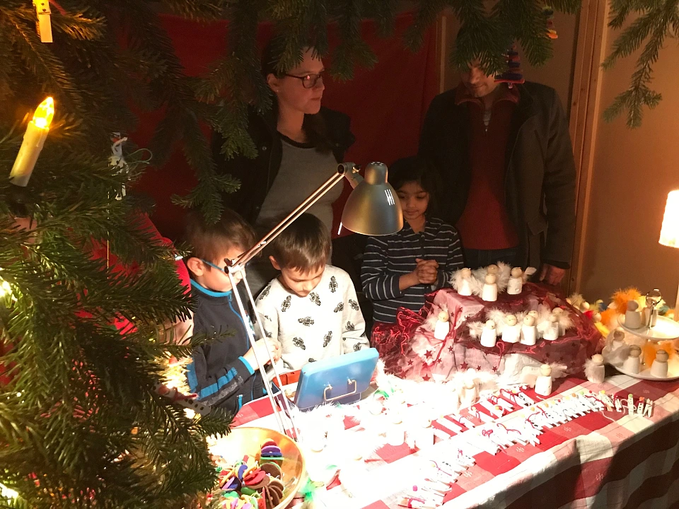 Auf dem Bild sind ein paar Kinder und Eltern an ihrem Stand auf dem Wintermarkt zu sehen