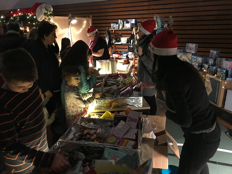Auf dem Bild sind ein paar Kinder und Eltern an ihrem Stand auf dem Wintermarkt zu sehen